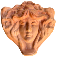 Terracotta sculpture of a face with flowing hair on a white background