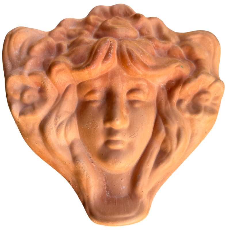 Terracotta sculpture of a face with flowing hair on a white background