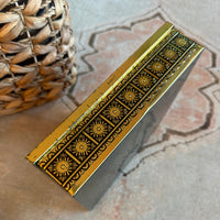 Decorative gold box with intricate patterns on a textured surface