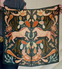 Person holding a dark green fabric with pink unicorn and nature-themed patterns.